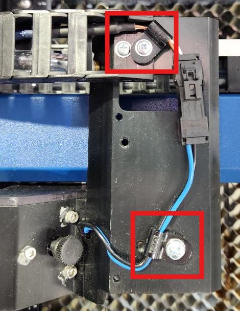 Lens carriage with screws and cable clamps visible before removal